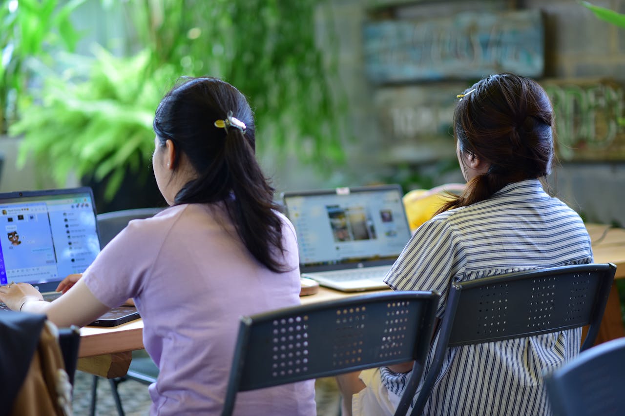 Two women working on laptops in a modern, green office space.